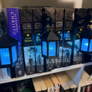 Three six-sided shelf lanterns glowing blue in front of books