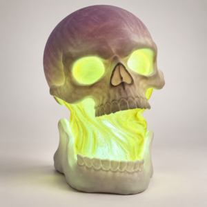 Three-quarter view of a skull lamp with yellow-green glowing eyes and jaw